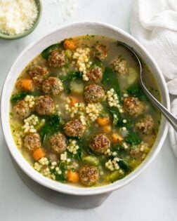 Italian Wedding Soup in a white bowl with meatballs, spinach, and acini de pepe.