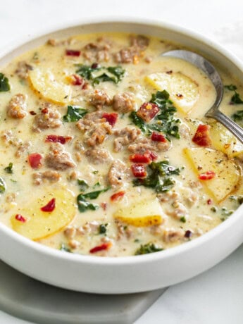 A white bowl of Zuppa Toscana Soup with bacon on top.