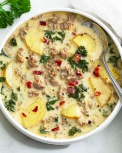 Zuppa Toscana Soup in a white bowl with a spoon on the side.