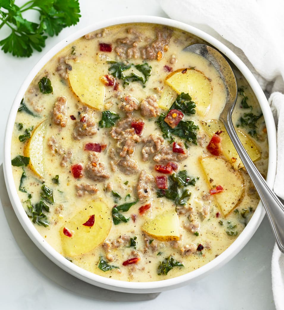 Zuppa Toscana Soup in a white bowl with a spoon on the side.