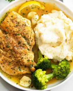 Pan Fried Chicken on a white plate with broccoli and mashed potatoes.