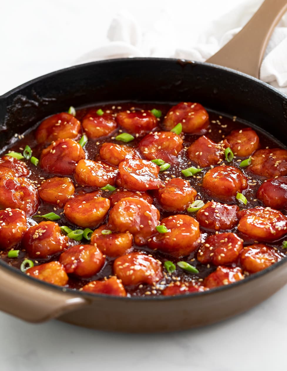 Firecracker Chicken in a skillet with a sticky sauce and green onions.