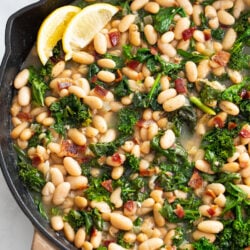Greens and Beans in a skillet with bacon and freshly sliced lemon.