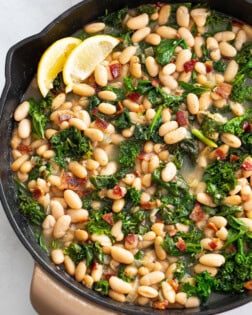 Greens and Beans in a skillet with bacon and freshly sliced lemon.