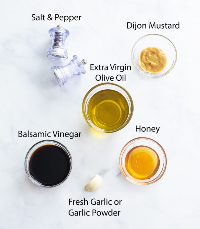 Ingredients for making Balsamic Vinaigrette on a white surface.