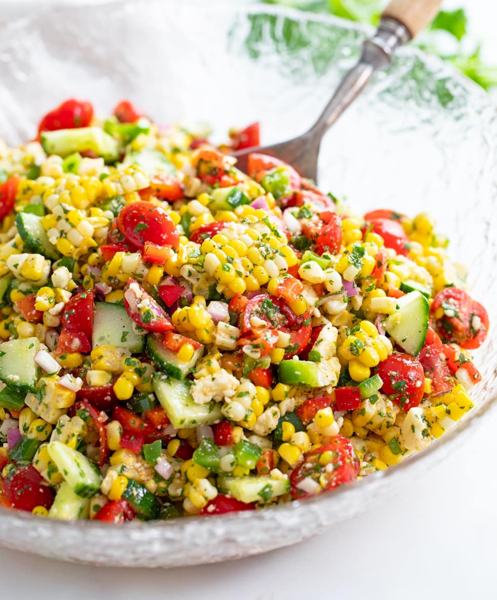 Corn Salad in a glass bowl with vegetables, cilantro, and dressing.