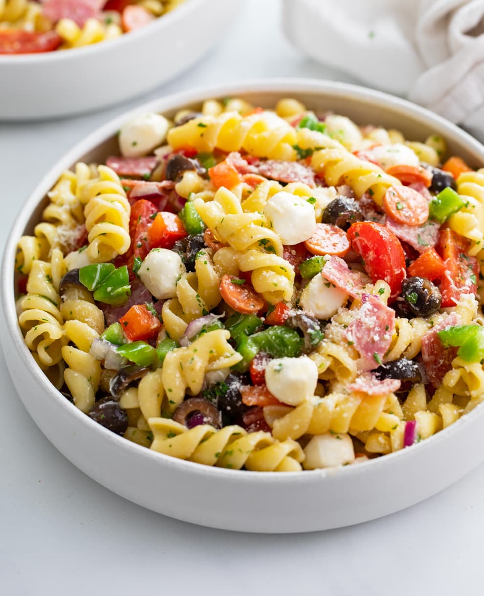 A white bowl filled with Italian Pasta Salad with meats, cheese, and vegetables.