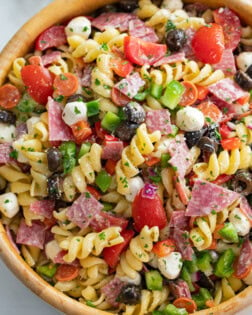 Italian Pasta Salad in a wooden bowl with spiral pasta, cheese, meat, and vegetables.