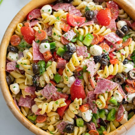 Italian Pasta Salad in a wooden bowl with spiral pasta, cheese, meat, and vegetables.