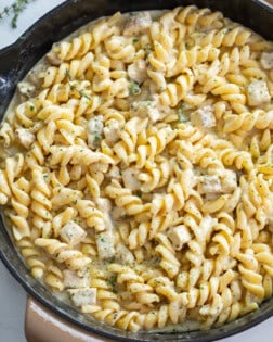 White Cheddar Chicken Pasta in a skillet with chopped parsley on top.