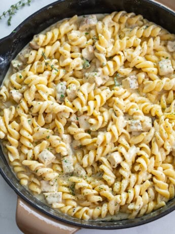 White Cheddar Chicken Pasta in a skillet with chopped parsley on top.