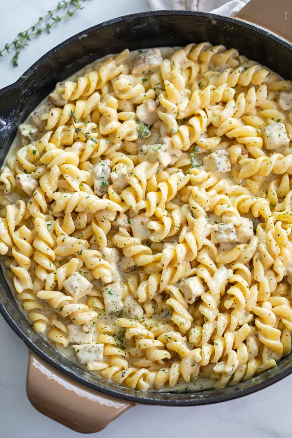 White Cheddar Chicken Pasta in a skillet with chopped parsley on top.