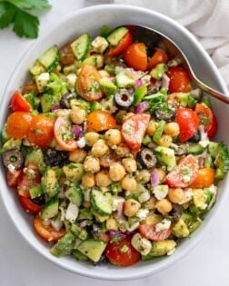 Chickpea Salad in a white bowl with a spoon on the side and dressing on top.