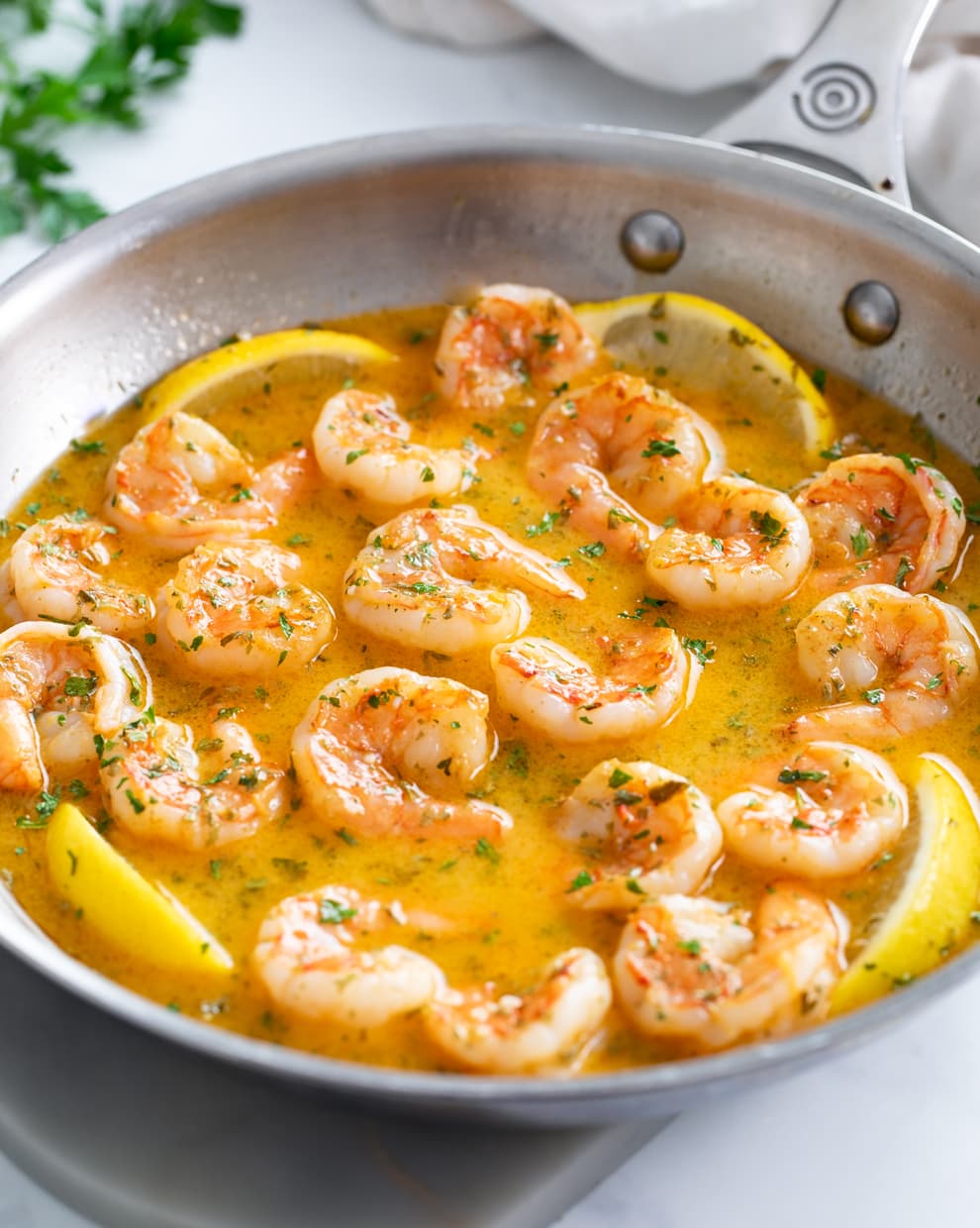 Garlic Butter Shrimp in a skillet with a butter sauce, parsley, and lemon wedges.