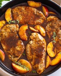 Peach Chicken in a skillet with fresh thyme and peach slices in a balsamic sauce.