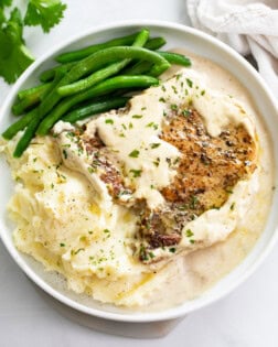 Ranch Pork Chops on a white plate with mashed potatoes and green beans.