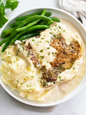 Ranch Pork Chops on a white plate with mashed potatoes and green beans.