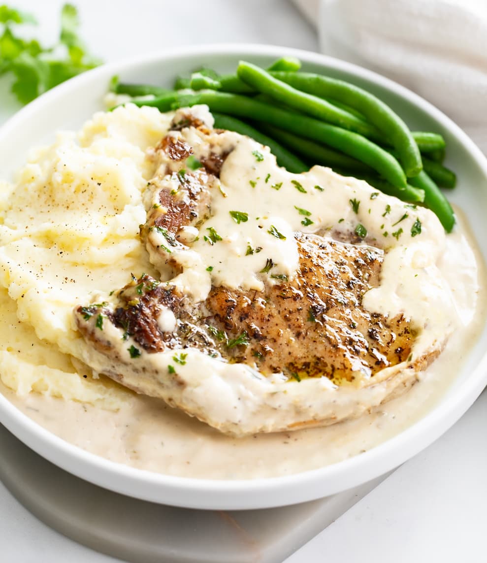 Ranch Pork Chops next to a scoop of mashed potatoes with green beans in the back.