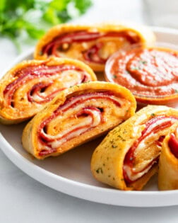 Slices of Stromboli on a white plate with parsley in the background.