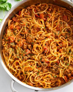 Taco Spaghetti in a skillet with taco meat and diced tomatoes with sauce.