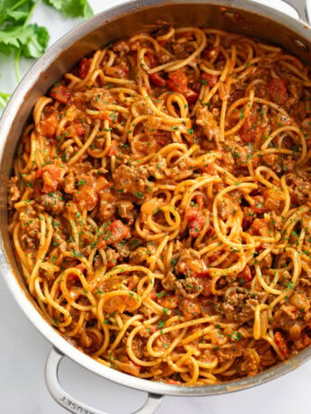 Taco Spaghetti in a skillet with taco meat and diced tomatoes with sauce.