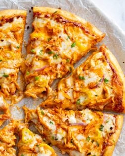 Buffalo Chicken Pizza cut into slices with buffalo sauce and blue cheese.