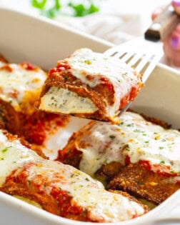 Eggplant Rollatini being pulled up from a casserole dish with a spatula.