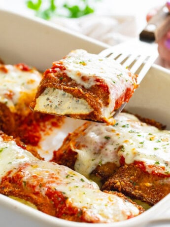 Eggplant Rollatini being pulled up from a casserole dish with a spatula.