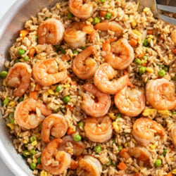 A skillet of Shrimp Fried Rice with shrimp, carrots, peas, and eggs.