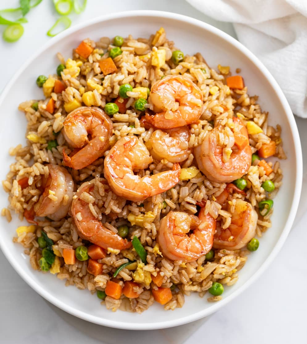 Shrimp Fried Rice on a white plate with vegetables and scrambled eggs.