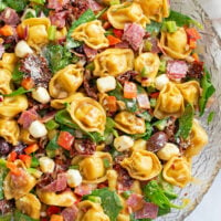 Tortellini Pasta Salad in a large glass bowl with Balsamic dressing and Italian ingredients.