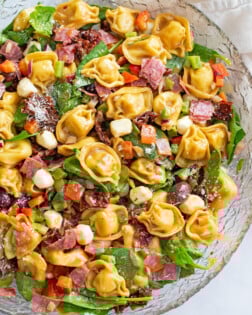 Tortellini Pasta Salad in a large glass bowl with Balsamic dressing and Italian ingredients.