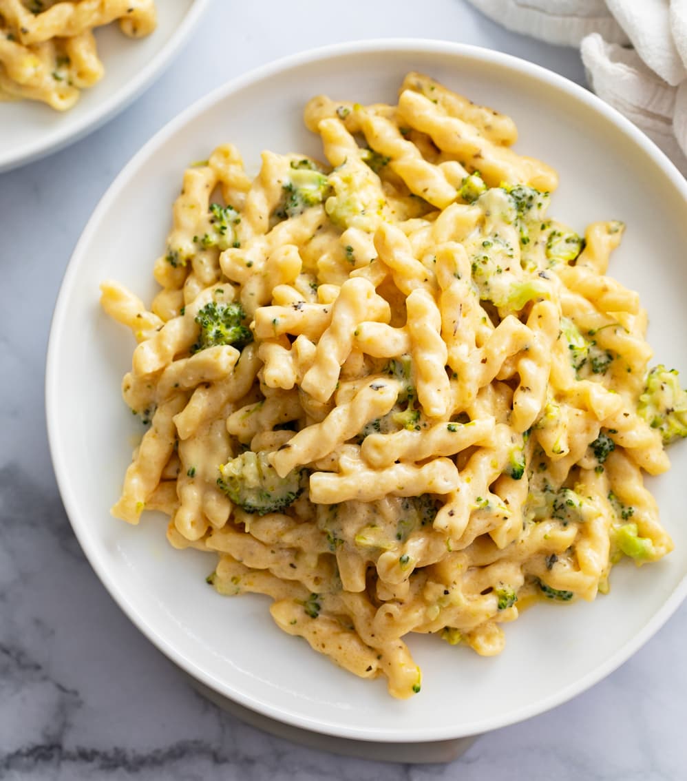 Cheese Pasta on a white plate with broccoli cheese sauce.