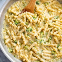 A skillet filled with Cheese Pasta with broccoli cheese sauce.