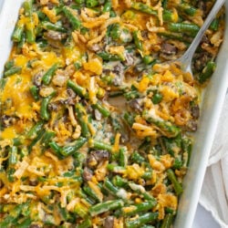 Green Bean Casserole in a white casserole dish with a spoon.