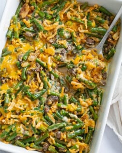 Green Bean Casserole in a white casserole dish with a spoon.