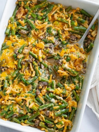 Green Bean Casserole in a white casserole dish with a spoon.