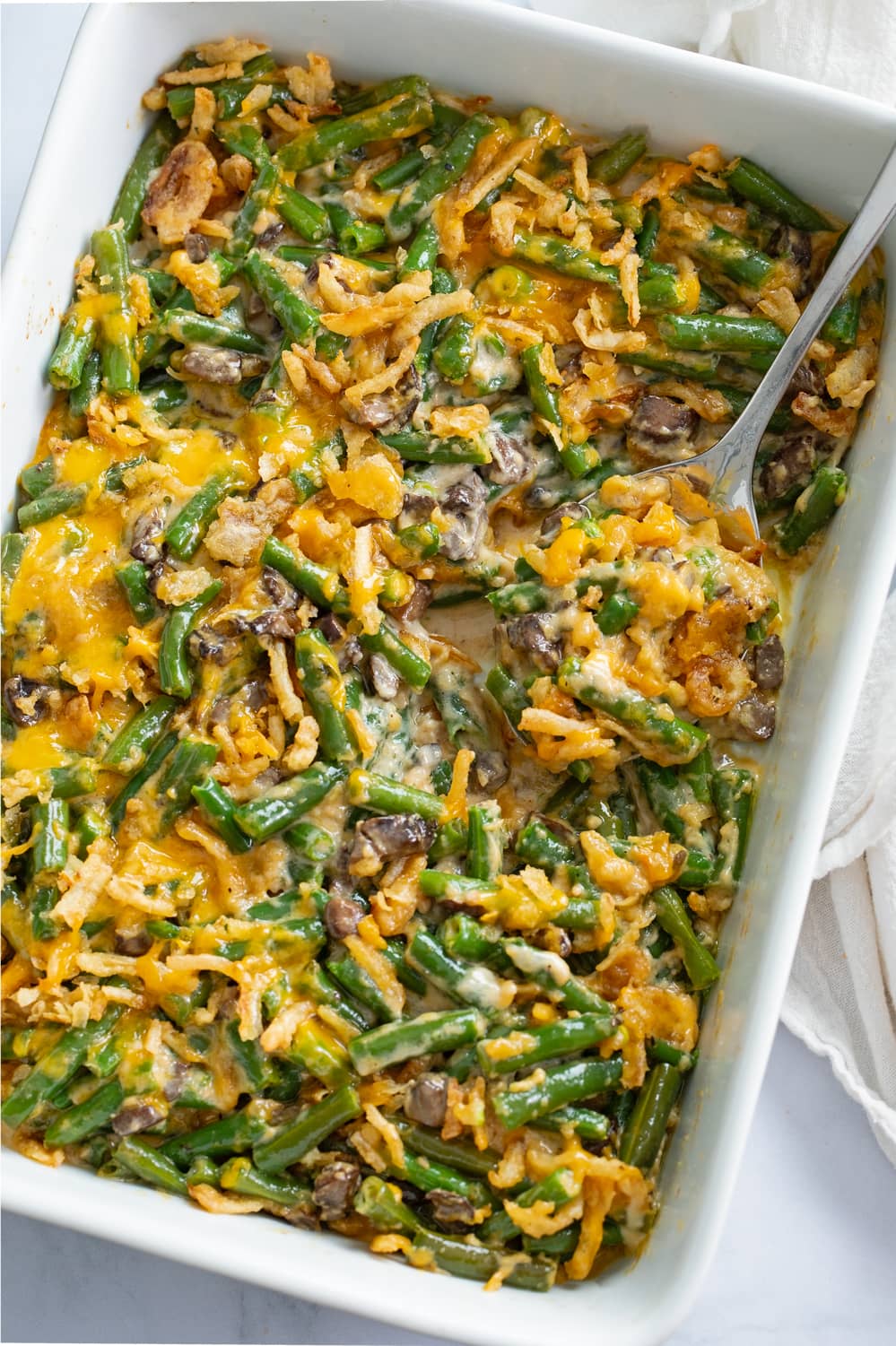 Green Bean Casserole in a white casserole dish with a spoon.