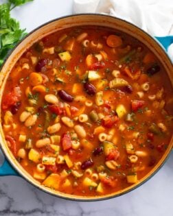 A soup pot of Minestrone Soup with fresh parsley on the side.