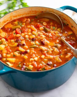 Minestrone Soup in a Dutch oven with a soup ladle on the side.