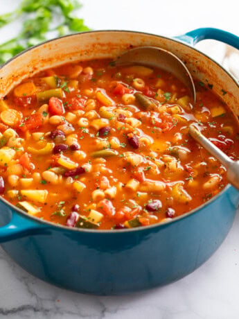 Minestrone Soup in a Dutch oven with a soup ladle on the side.