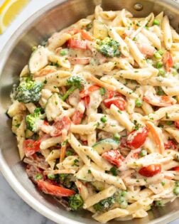 Pasta Primavera in a skillet with vegetables, ziti, and cream sauce.