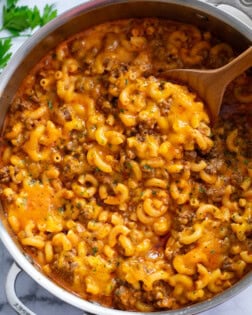 A skillet of Beefaroni with a wooden spoon in it.