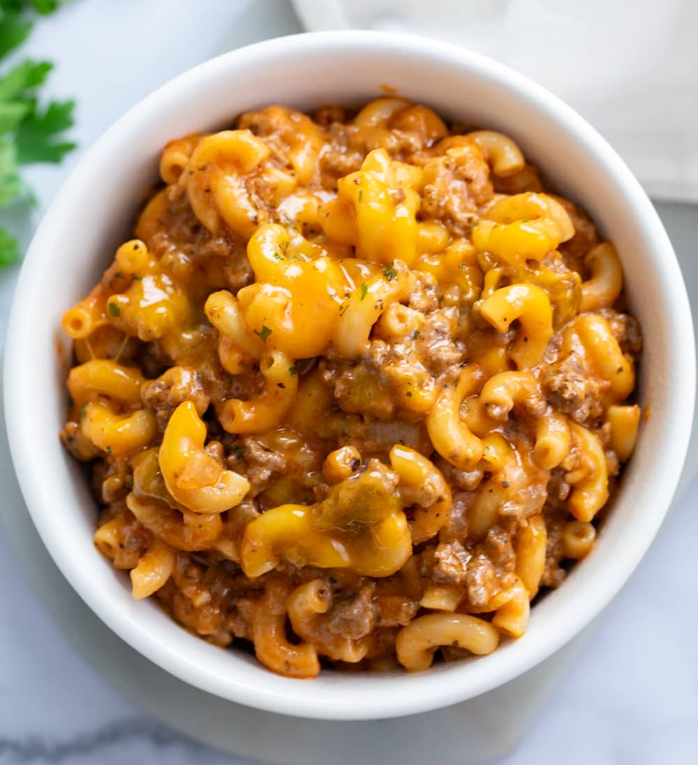 Beefaroni in a white bowl with cheese on top.