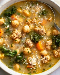 Chickpea Soup in a bowl with Parmesan cheese on top and a spoon on the side.