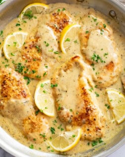 Lemon Garlic Chicken in a skillet with sauce, lemon slices, and parsley.