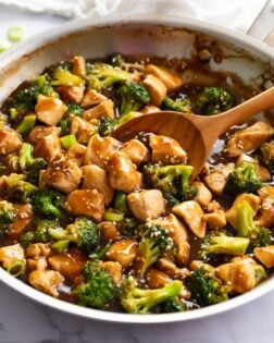 Chicken Teriyaki with broccoli in a skillet with a wooden spoon scooping it up.