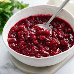 Cranberry Sauce in a white bowl with a spoon.