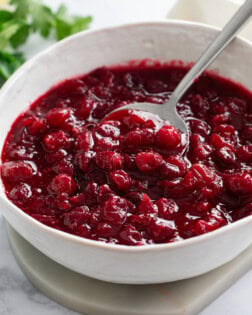 Cranberry Sauce in a white bowl with a spoon.