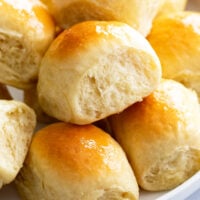 A pile of Fluffy, soft dinner rolls with honey butter on top.